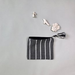 Small black and white striped clutch bag with tassel detail.