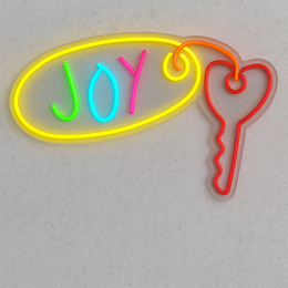  Colorful neon 'Joy' sign with a heart-shaped key, wall-mounted lighting fixture with a blue and white design, and a modern dining table with wooden chairs.