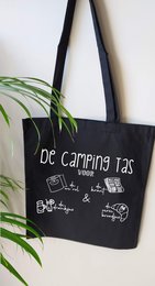 A black cotton tote bag with the text "De camping tas" (The camping bag) and various camping-related icons printed on it. The bag appears to be made of durable cotton material and has long black handles for comfortable carrying.