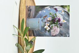 Colorful bouquet of wildflowers in a rustic metal vase on a wooden table.