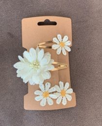 Set of 61 white daisy-shaped hair clips for kids. Includes a variety of sizes and shapes to accessorize any hairstyle.