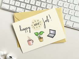 A greeting card with the text "happy new job!" and illustrations of a potted plant, a coffee mug, and a laptop.