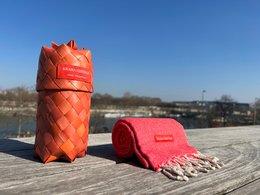 Warm coral orange scarf with woven texture and fringe details.