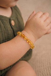 Round, polished amber beads in a 14cm bracelet in a citrus color.