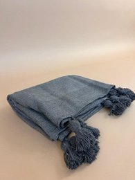 Gray plaid throw blanket with pompom tassels, cozy woven textile, decorative fringe trim.