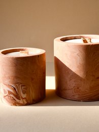 Cylindrical wax candles in earthy tones with a rustic, handcrafted appearance. The candles feature a simple, minimalist design that would complement a variety of home decor styles.