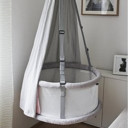A classic white crib with a round, elevated design and adjustable straps for safety and convenience.