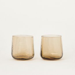 Two amber-colored tumblers with a textured glass design, suitable for cocktails or other beverages.