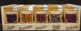 This image shows a wooden crate or display containing various types of nuts and spices. The crate is divided into 5 compartments, each containing a different product. The products appear to be different flavors or varieties of nuts, such as almonds, cashews, and other types. The description should focus on the key details of the products visible in the image, without identifying any individuals.
The image shows a wooden crate or display containing a variety of nuts and spices. The crate is divided into 5 compartments, each containing a different product. The products appear to be different flavors or varieties of nuts, such as almonds, cashews, and other types. The crate is labeled with the text "SET OF 5 FLAVOURS X 10 PIECES 50G EACH."