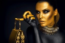 A poster featuring a close-up portrait of a woman with dramatic gold makeup and jewelry, holding a decorative gold lamp.