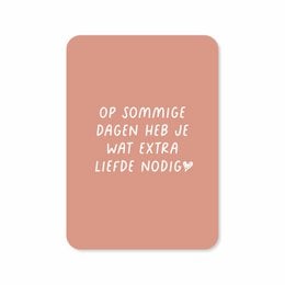 A greeting card with the text "Op sommige dagen heb je wat extra liefde nodig" (On some days you need a little extra love) in a handwritten-style font on a peach-colored background.