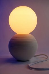 Spherical table lamp with a white globe and a textured base in shades of blue. Provides warm, ambient lighting.