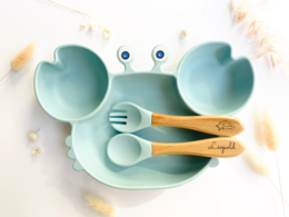 Crab-shaped kids' meal set in navy blue, sky blue, pink, khaki, ochre, and sand colors with fork, spoon, and plate.