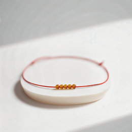 Fiery Essence Five Bracelet - A delicate red cord bracelet with five amber-colored beads, creating a stylish and eye-catching accessory.