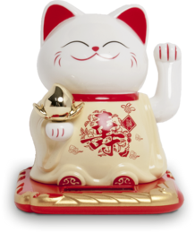 A white and red ceramic figurine of a lucky cat, also known as a Maneki-neko. The cat has a smiling expression and is waving its paw. The figurine is sitting on a red and gold base.