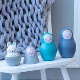 A set of colorful, stacking baby toys with a chiming feature. The toys feature a round, nesting design in shades of blue and white, with smiling faces painted on each piece.