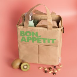 Beige canvas lunch bag with green "BON APPETIT" text and zipper closure. Suitable for carrying food and drinks, with a casual and stylish design.