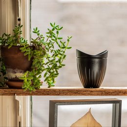 Black ceramic mug with lid, perfect for coffee or tea on the go. Features a sleek, minimalist design.