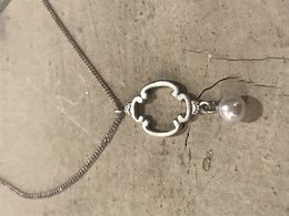 Silver necklace with a clover-shaped pendant and a pearl charm.
