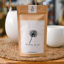 A small brown paper bag with a white label that says "Happy Birthday" in cursive text. The bag appears to contain some kind of tea or other product.