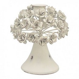 A white ceramic candlestick with a bouquet of white flowers on top, displayed in a rustic wooden setting.