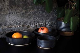 Large and small black ceramic serving bowls with riffled texture, suitable for a variety of dishes.