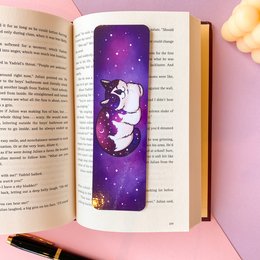 Laminated bookmark with a whimsical astrocat design featuring a cat in a starry night sky. The bookmark is made of durable laminated material and would be a charming addition to any book lover's collection.