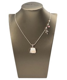 Silver-toned necklace with a circular pendant featuring a mix of clear and gray stones. Matching stud earrings included.