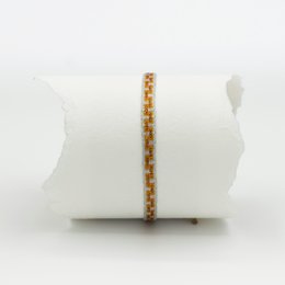 Delicate gold-toned bracelet with small round charms in a repeating pattern.