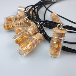 Amber glass bottle pendant necklace with amber-colored contents.