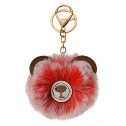 A red and white furry keychain with a bear design and a metal charm.
