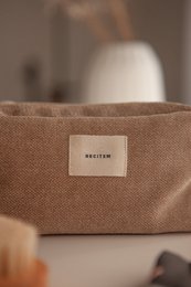 Beige toiletry bag with "Baxter" label, made of durable material, suitable for storing personal care items.
