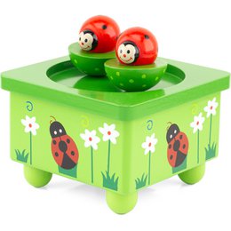 A green wooden music box with a ladybug design, featuring a red ladybug figure on a green platform with white flowers.