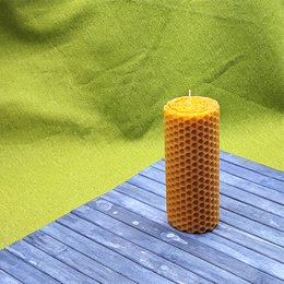 Tall, cylindrical beeswax candle with a honeycomb texture and a warm, natural yellow color.