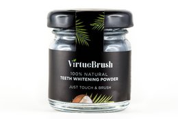 Teeth whitening powder in a glass jar with a black and green label. The powder is a natural, plant-based formula for whitening teeth.