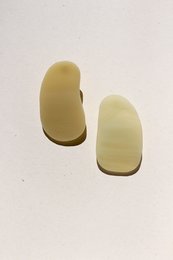 Minimalist statement earrings in a soft, muted green color. Geometric, oval-shaped design with a simple, modern aesthetic.