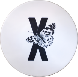 A round white plate with a black letter "X" and a butterfly graphic.