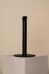 Black and white kitchen roll holder with a cylindrical shape and a round base.