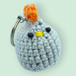 Gray crocheted keychain with orange flower decoration and metal ring.