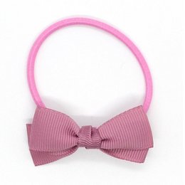 Small bow elastic hair accessory in rosy mauve color, suitable for kids.