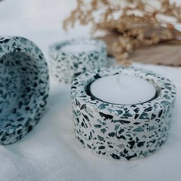 White speckled terrazzo tealight holder, round cylindrical shape, modern minimalist design, concrete-like material texture.