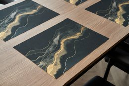 Rectangular table placemats in dark colors with abstract, wavy patterns. The placemats appear to be made of a durable material, possibly wood or a wood-like composite. The patterns feature shades of gray, black, and gold, creating a modern, minimalist aesthetic.