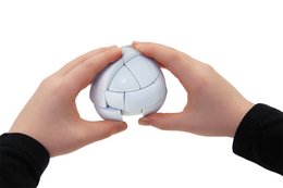 A white, egg-shaped puzzle toy with a cracked surface and colorful graphics on the packaging. The puzzle can be manipulated and twisted to reveal different patterns and shapes.