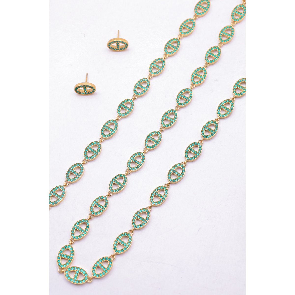 Ensemble assorti comprenant un collier, un bracelet en chaîne et une paire de boucles d'oreilles puces. Chaque bijou est composé d'une succession de maillons en forme de maille marine entièrement pavés de petits strass scintillants.