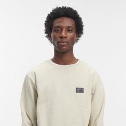 Stone beige crew neck sweater with small logo patch, long sleeves, casual men's style