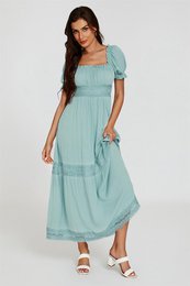  A long, flowing blue maxi dress with lace detailing and puff sleeves. The dress has a square neckline and a tiered skirt, creating a romantic, feminine silhouette.