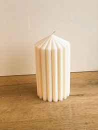 Large, ribbed, pillar candle available in white, pink, and lavender colors.