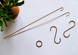 Brass accessory with curved, hook-like design. Suitable for hanging plants or other decorative items.