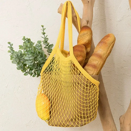 A reusable cotton tote bag in various colors, including cream, red, yellow, green, black, lilac, sky blue, and orange. The bag has long handles and is designed for carrying groceries or other items.