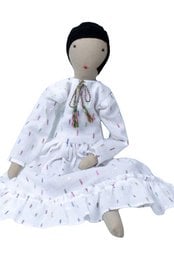 A soft, plush doll with a white dress featuring a delicate floral pattern. The doll has a simple, minimalist design with a neutral color palette and a serene expression.